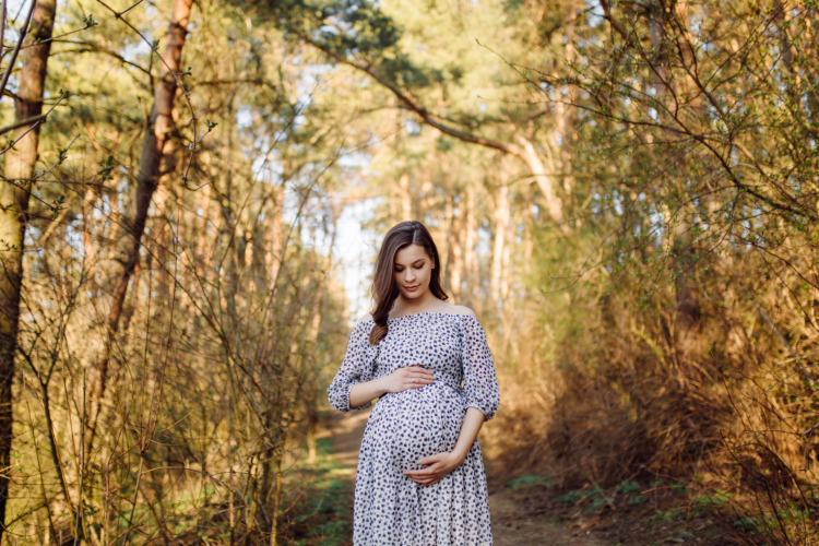 Young pregnant woman relaxing in park outdoors