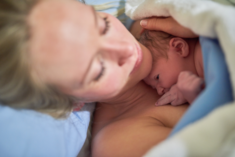 Shot of a beautiful young mother lying in bed with her newly born baby girl in the hospital.