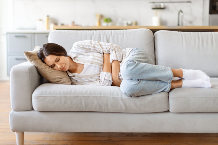 Stomach Ache. Sick Young Female Suffering From Acute Abdominal Pain At Home, Millennial Woman Touching Belly While Lying On Couch, Having Menstrual Pain Or Problems With Digestion, Free Space